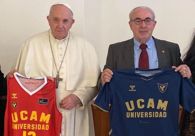 El Papa Francisco y José Luis Mendoza posan con camisetas de los equipos de baloncesto y fútbol de la institución.