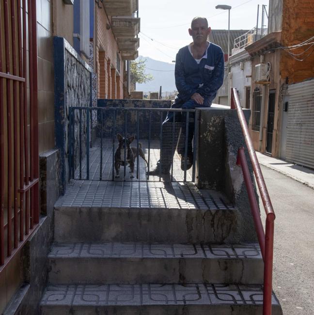 Pedro López, sentado junto a su perro en las escaleras de acceso a su casa, en la calle del casino.