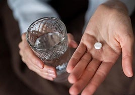 Una mujer se toma un analgésico para aliviar el dolor.