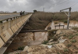 Dos personas contemplan la bajada de agua por la rambla del Albujón tras las primeras grandes lluvias en marzo de este año.
