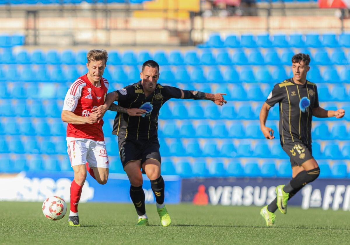 Loren Burón, jugador del Real Murcia, pugna por un balón con San Emeterio, del Intercity.