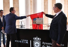 El alcalde de Murcia, José Ballesta, y el delegado comercial de Loterías y Apuestas del Estado en la Región, José Laorden, destapan el décimo de la Lotería Nacional con la imagen de la ciudad.