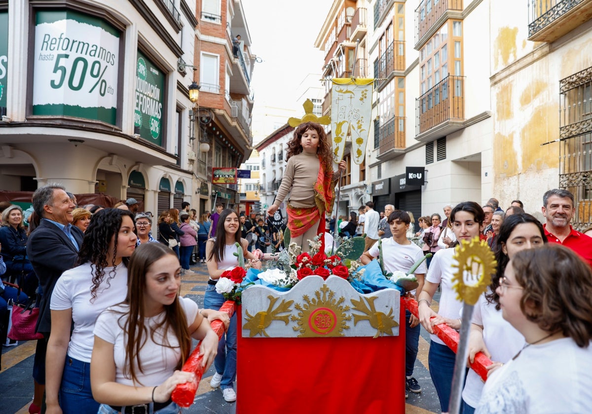 Un niño representa a Jesús Resucitado en su trono en la procesión de papel.