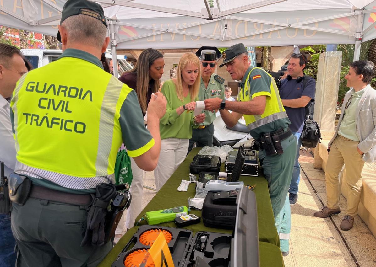 Imagen secundaria 1 - Izquierda: La delegada del Gobierno, junto a la alcaldesa de Alhama, acompañadas por el Coronel Jefe de la Benemerita atendiendo explicaciones de como se realiza un control de drogas. Derecha: Helicóptero de la Guardia Civil sobrevolando la muestra.