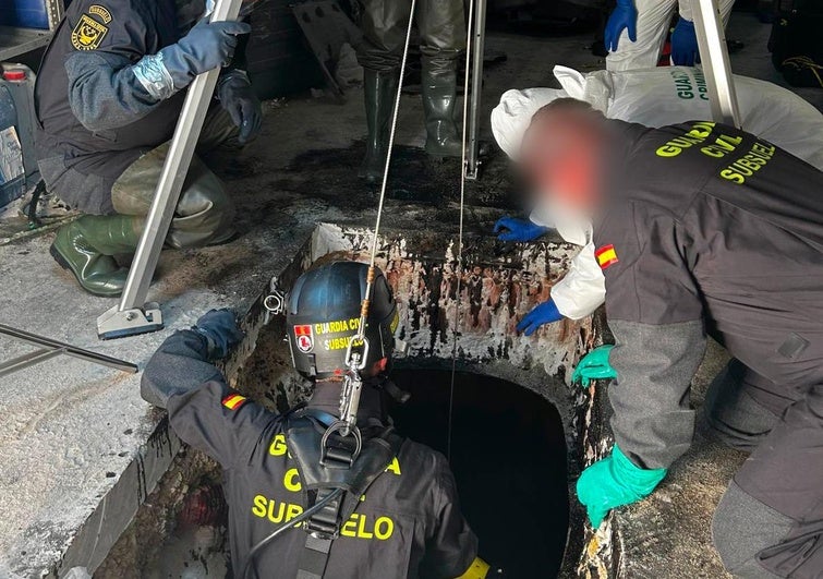 Un agente de la Guardia Civil se introduce en el depósito de aceite donde se encontraron los restos humanos.