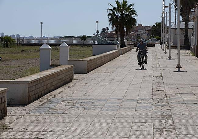 Un ciclista pasa sobre las baldosas rajadas del paseo de Los Nietos.