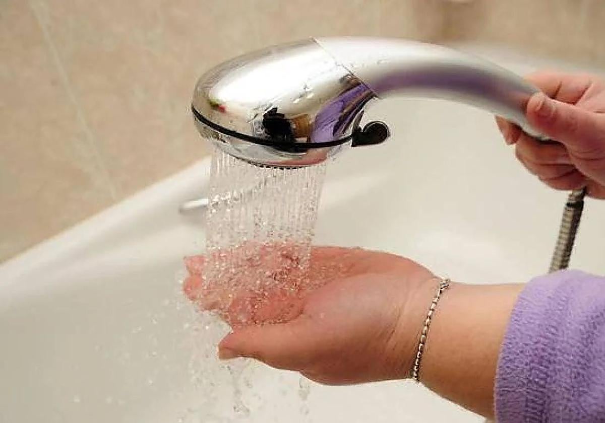 Imagen de archivo de una mujer comprobando la presión de la ducha.