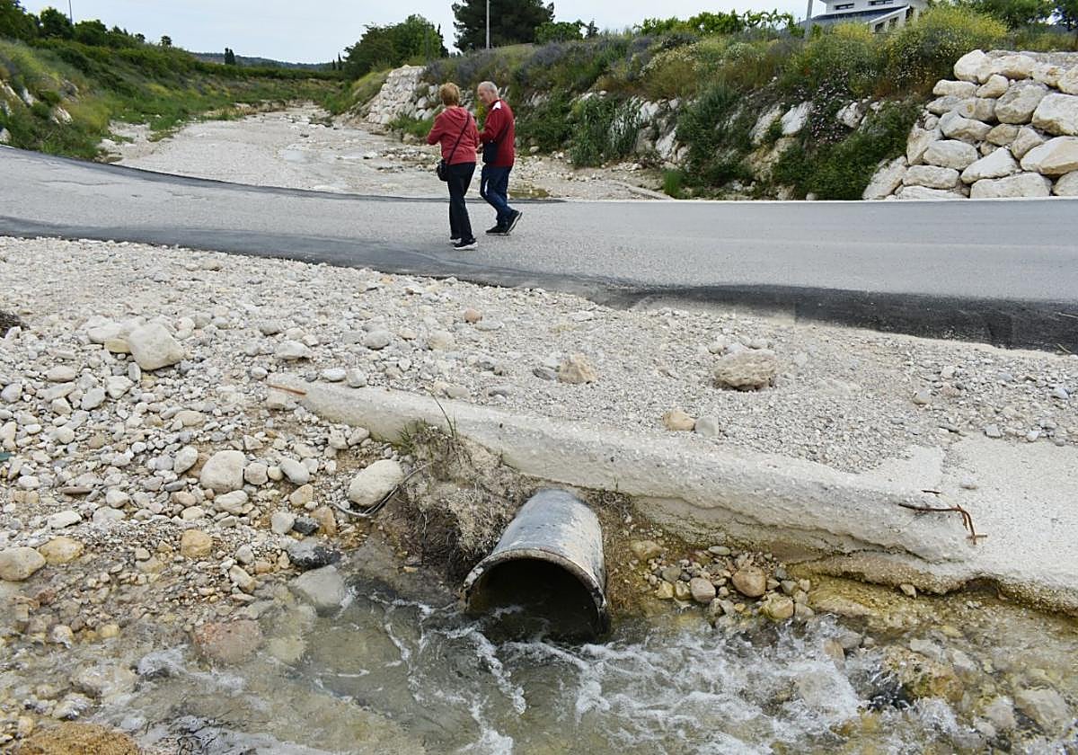 Dos vecinos caminan por la carretera de acceso a la urbanización Nueva Caravaca, ayer.