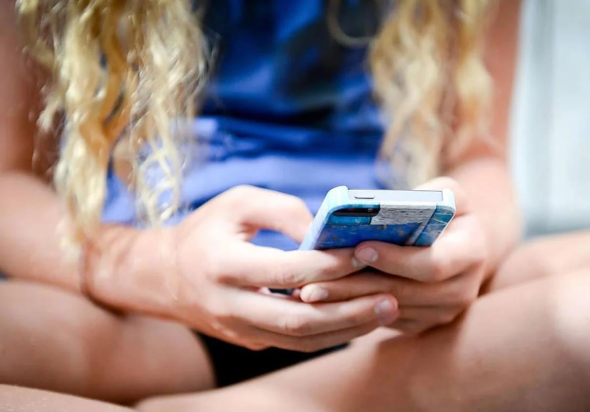Una chica sostiene un teléfono móvil.