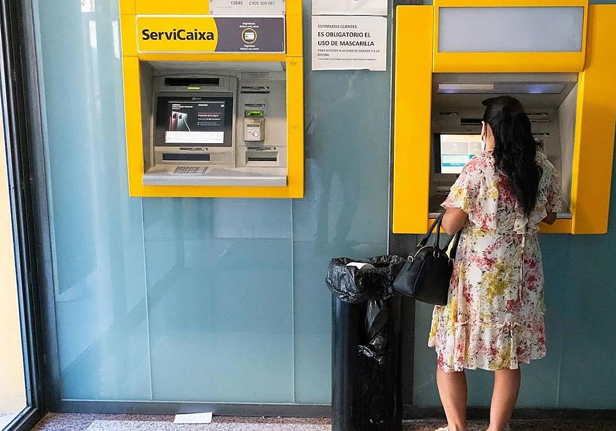 Una mujer sacando dinero de un cajero, en una imagen de archivo.