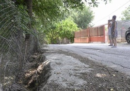 Dos de los afectados, a la entrada de su vivienda, junto al carril que está sucumbiendo hacia el canal de la acequia.