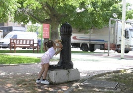 Una niña bebe agua del suministro municipal en una fuente pública ubicada en el parque de Fofó, en Murcia.