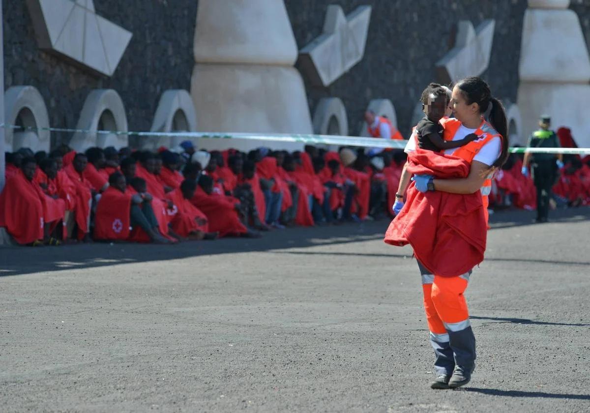 Una voluntaria de Cruz Roja lleva en brazos a un menor llegado en patera en una imagen de archivo.