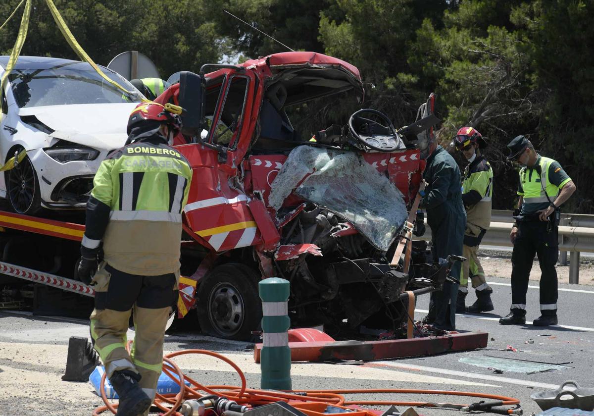 Bomberos y agentes de la Guardia Civil, junto al camión grúa implicado en el accidente mortal.