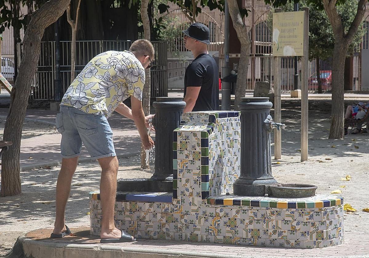 Unos hombres se refrescan en una fuente de Cartagena, en una imagen de archivo.