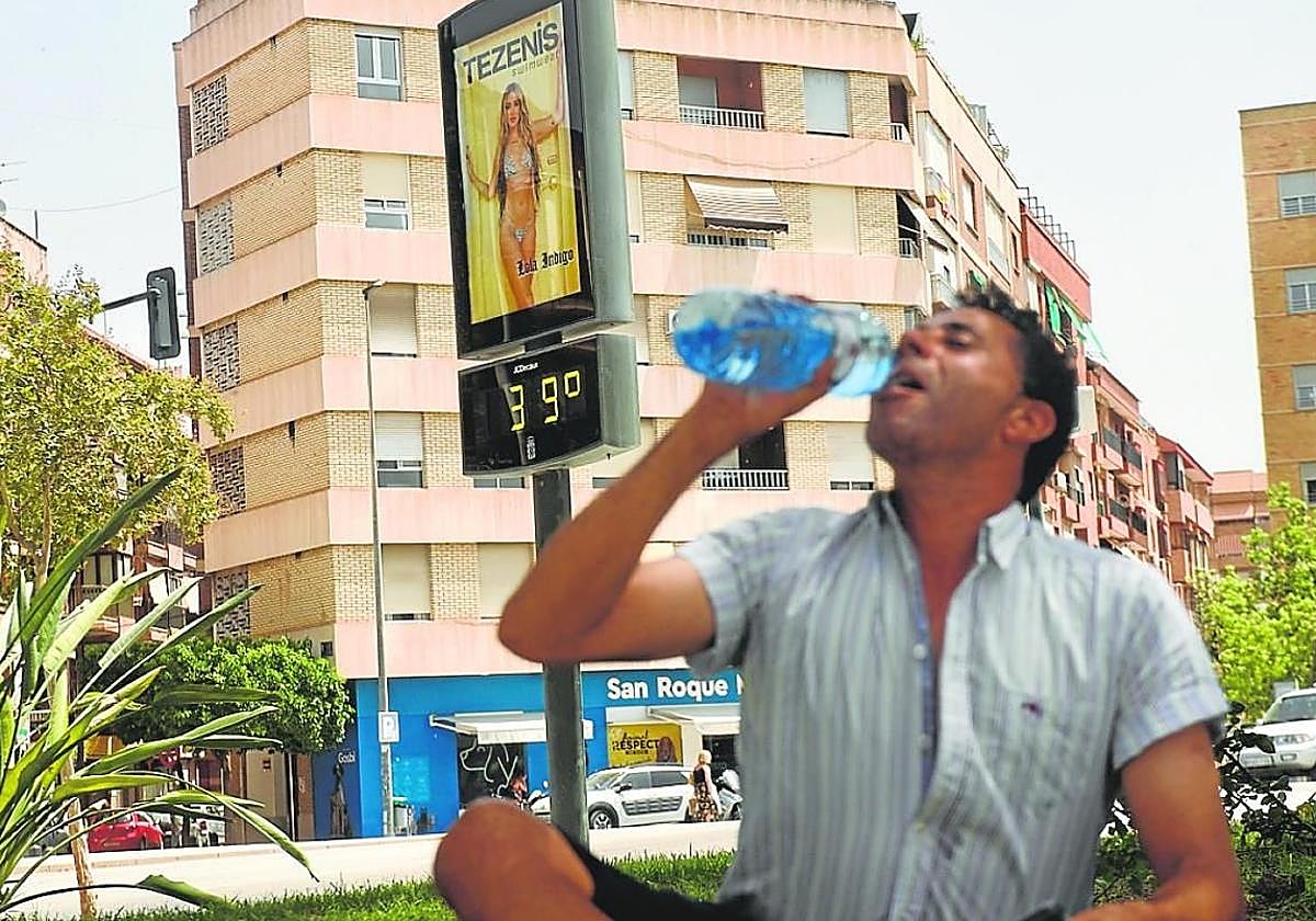 Un hombre bebe agua junto a un termómetro en Murcia, en una imagen de archivo.