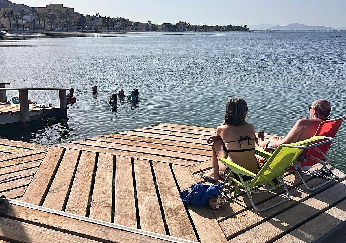 Dos bañistas toman el sol sentadas esta semana en uno de los pantalanes de Los Urrutias.