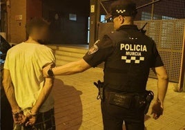 Un agente de la policía junto al detenido.