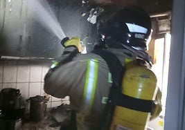 Un bombero refresca la cocina afectada.