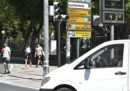 Varios peatones cruzan la calle junto a un termómetro que marca 43 grados.