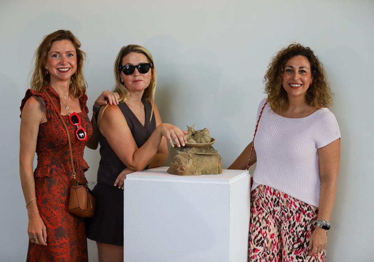 Tres asistentes a la subasta de la obra del artista Joaquín Ganga acarician la escultura.