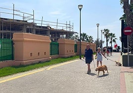Dos turistas pasean esta semana frente a las obras de la urbanización, reactivadas recientemente.