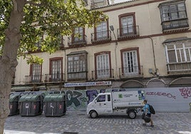 Un hombre camina en dirección a los contenedores de basura instalados actualmente frente al inmueble.
