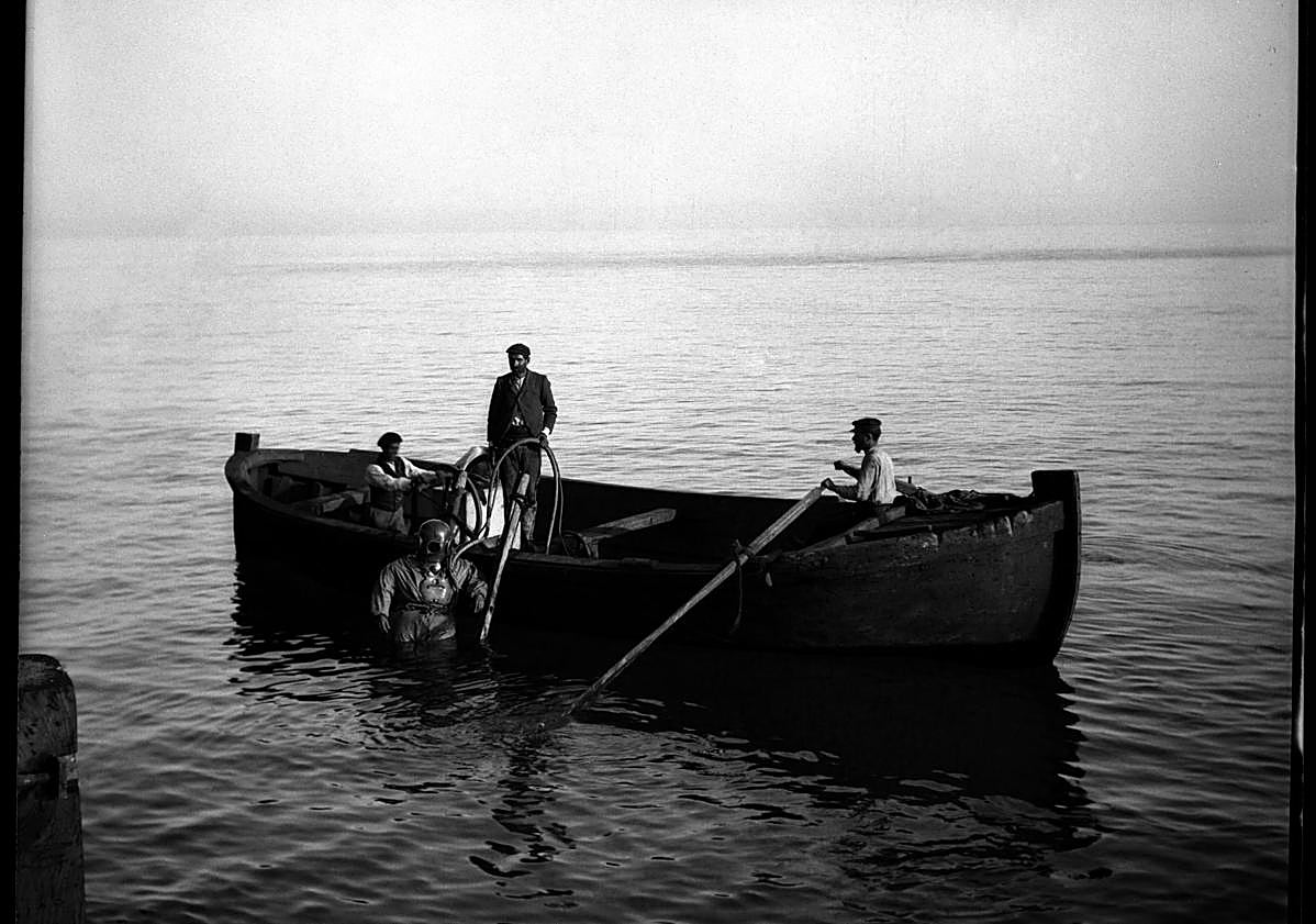 Imagen principal - El Hornillo. Bote del buzo, fijando defensas en El Hornillo, según descripción del propio autor (c. 1902). | Isla del Fraile. Panorámica de la isla, con una boya en primer término (c. 1903). | Familia. Hijos de Gillman sentados junto a la orilla en la playa de El Hornillo (1899). 