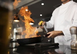 Un chef ultima una receta con un soplete de cocina.