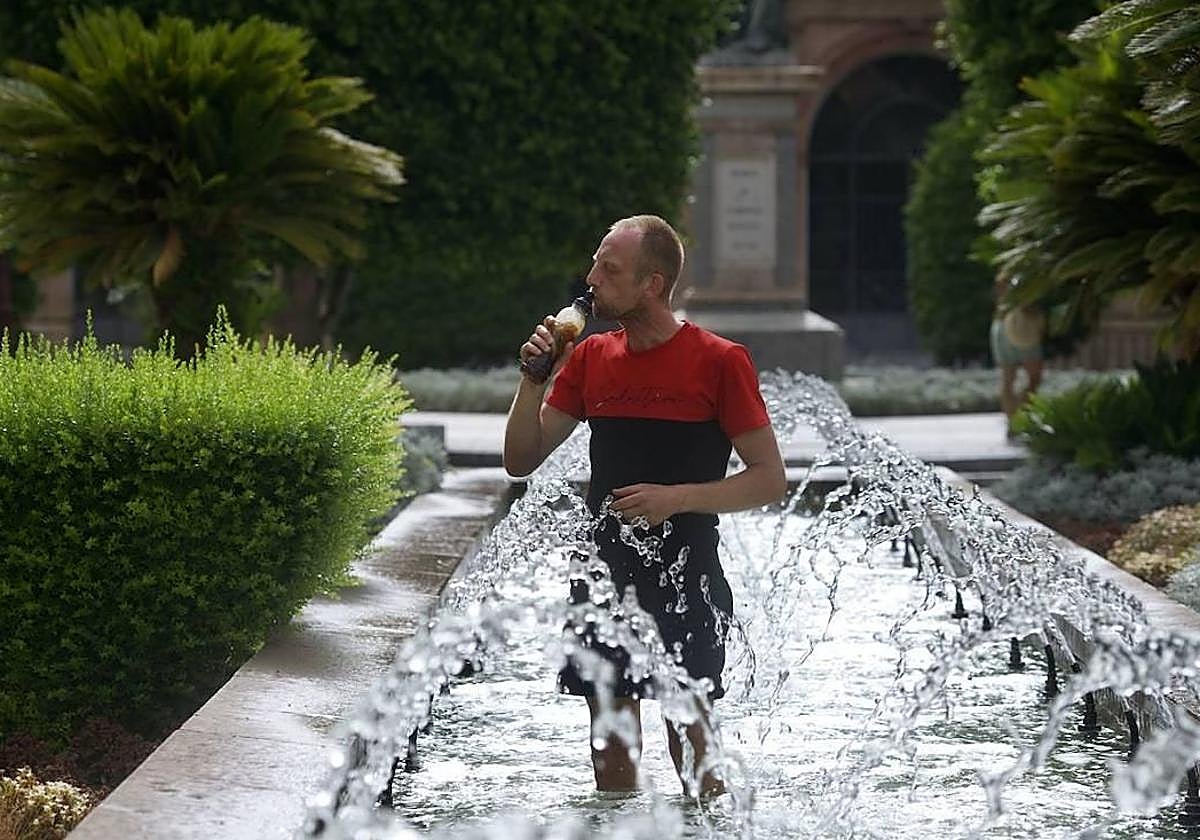 Un hombre refrescandose en una fuente durante una ola de calor en Murcia.