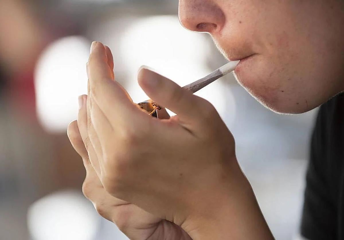 Una joven encendiéndose un cigarrillo.