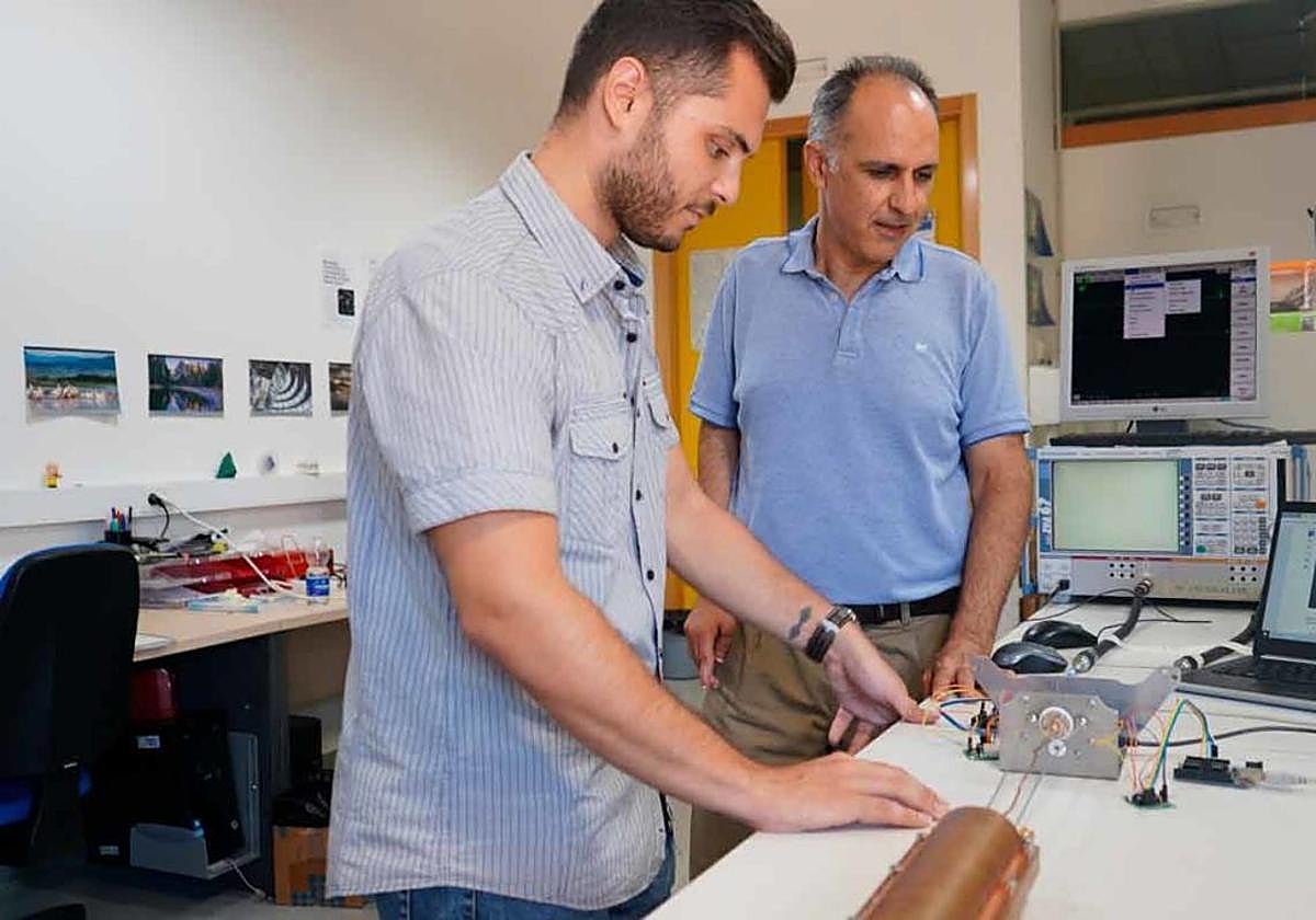 El autor de la tesis y su director observan la toma de medidas con la cavidad resonante a escala que han construido.