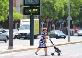 Una mujer pasa junto a un termómetro que marca 42 grados en Murcia, este verano.
