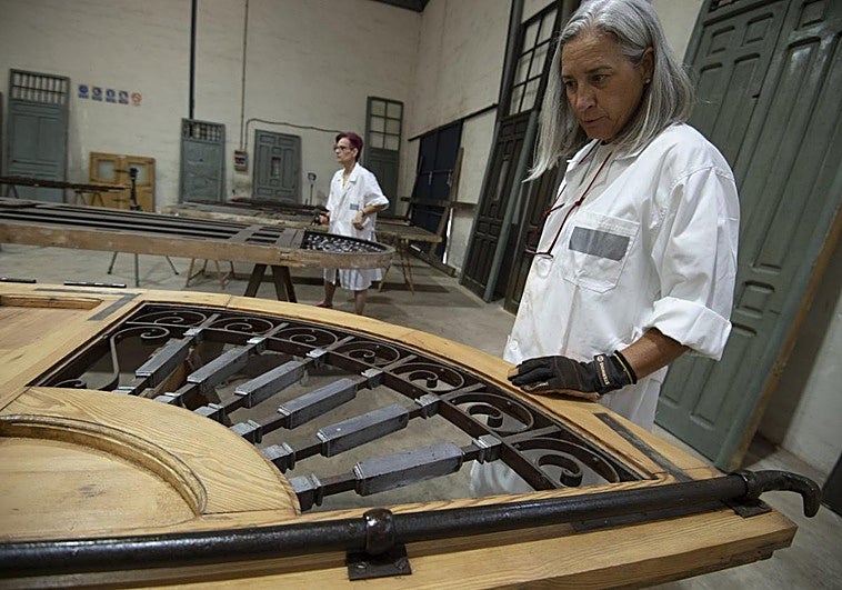 Mara Noguera, al fondo, y Montse Pasqual del Riquelme trabajan en la rejería de plomo de las puertas de entrada.