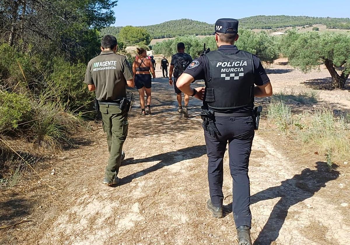Un agente medioambiental y otro de la Policía Local de Murcia acompañan a los senderistas extraviados este domingo.