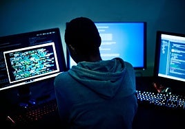 Una persona frente a varios ordenadores, en una foto de archivo.