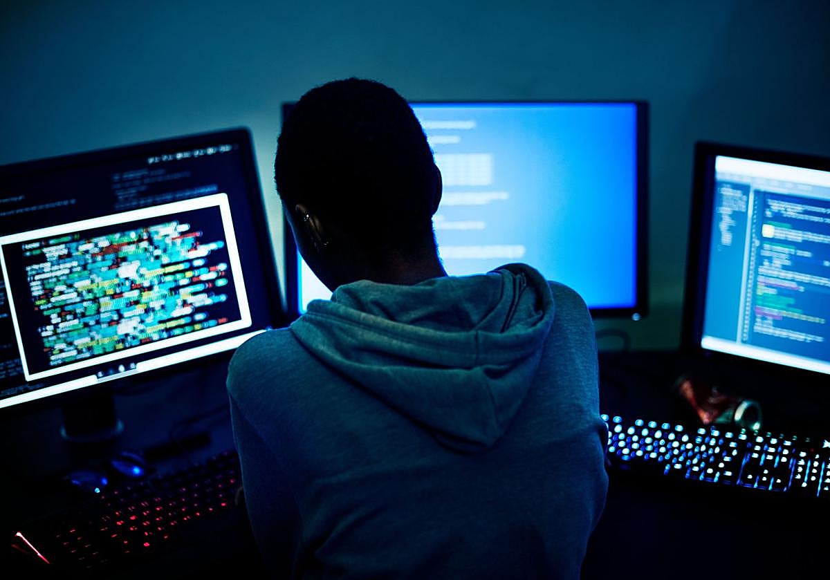 Una persona frente a varios ordenadores, en una foto de archivo.