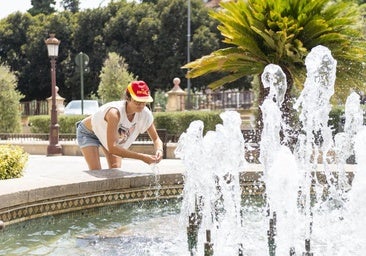Una mujer se refresca en la fuente de la Glorieta de Murcia.