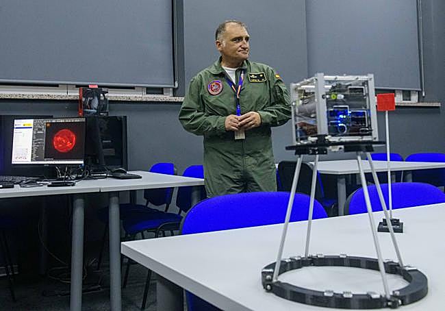 El comandante López y en primer término, un satélite de pruebas.