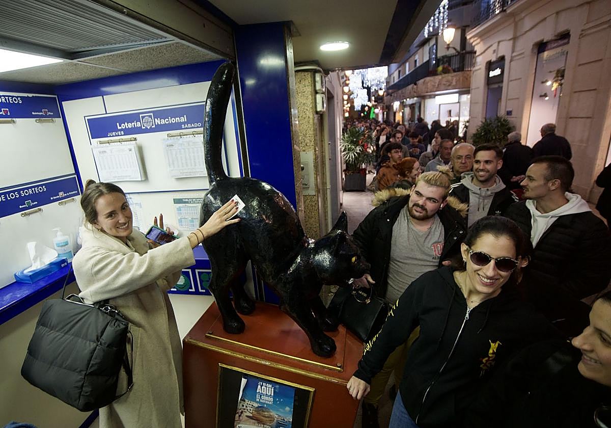 Una chica restriega su décimo por el lomo del gato negro que decora la administración murciana del mismo nombre.
