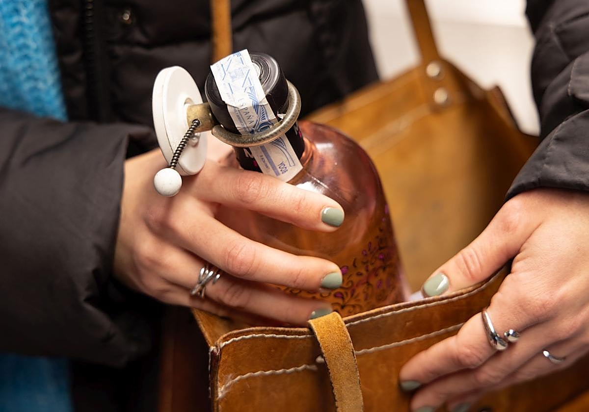 Una mujer comprando una botella de alcohol.