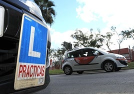 Dos coches de autoescuela circulan por una calle en Murcia.