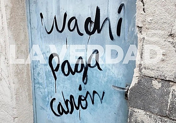 Pintada en la puerta de la vivienda incendiada en mayo de 2024, donde murieron tres personas.