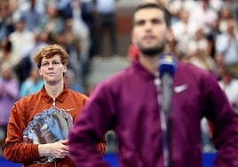 Jannik Sinner, en segundo plano, escuchando el discurso de Carlos Alcaraz tras la final del domingo.