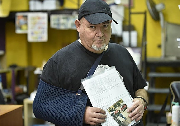 Andrés, en su copistería y con el brazo en cabestrillo, muestra la foto del que asegura que fue su agresor.