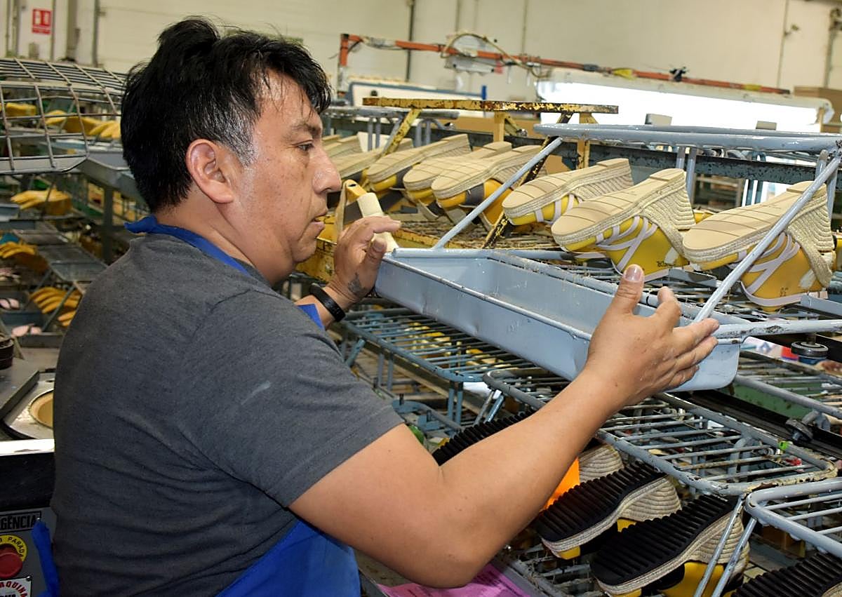Imagen secundaria 1 - 1. Un trabajador revisa el calzado en los moldes de la fábrica. 2. Una operaria adpta la suela de yute. 