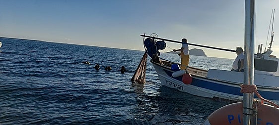 Un momento de la operación conjunta de buzos y pescadores para retirar la red.