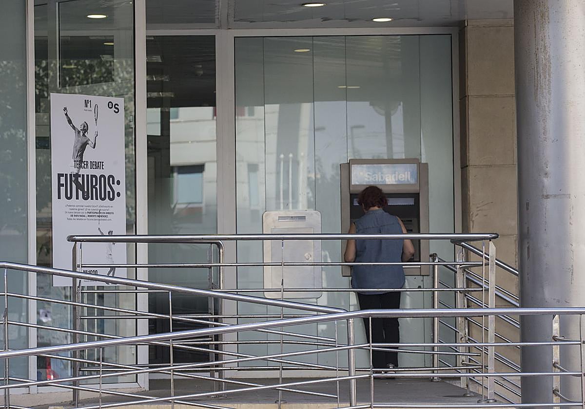 Una mujer sacando dinero de un cajero automático, en una imagen de archivo.