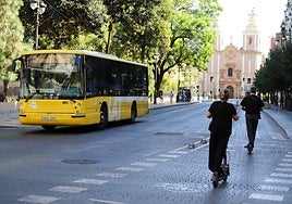 Un autobús circula por la Alameda de Colón, en Murcia, mientras dos usuarios de patinete usan el carril-bici.