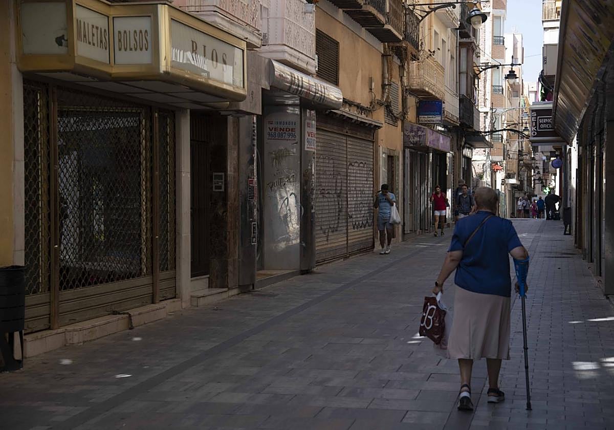 Transeúntes pasan frente a varios de los bajos comerciales que permanecen cerrados en San Fernando, una de las calles comerciales más antiguas de la ciudad.